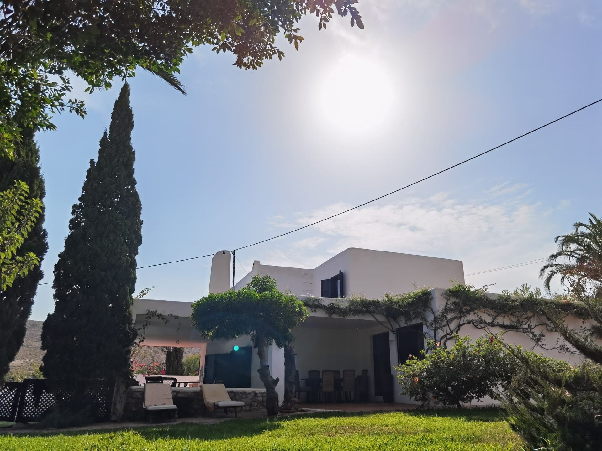 El sol brilla intensamente sobre una casa blanca.