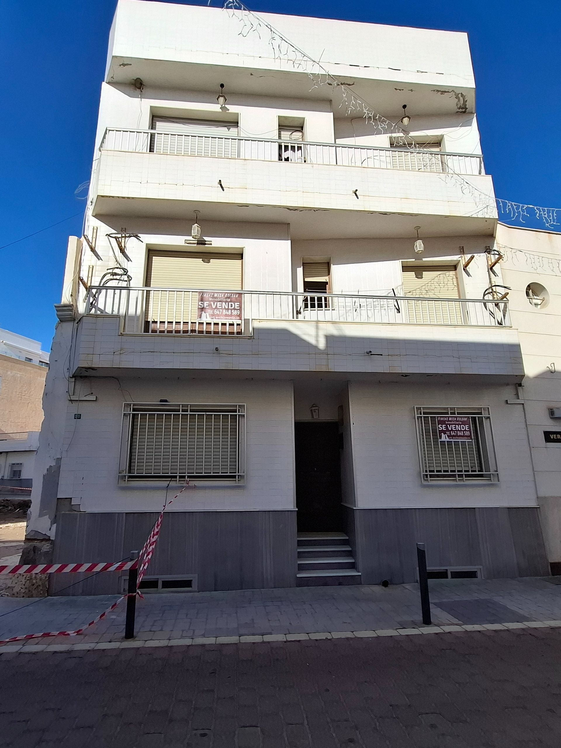 Un edificio blanco con un balcón y un cartel que dice 'alquiler'.