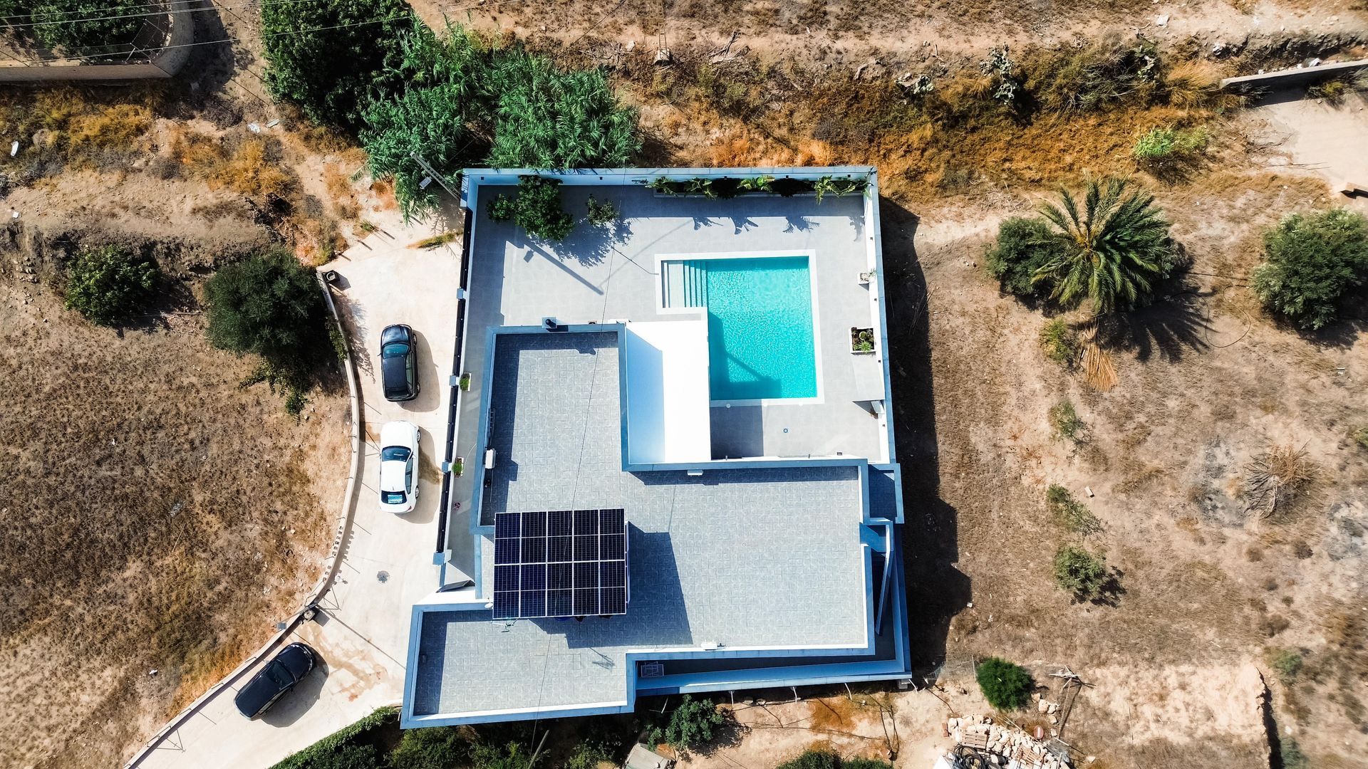 Una vista aérea de una casa con piscina en medio de un campo.