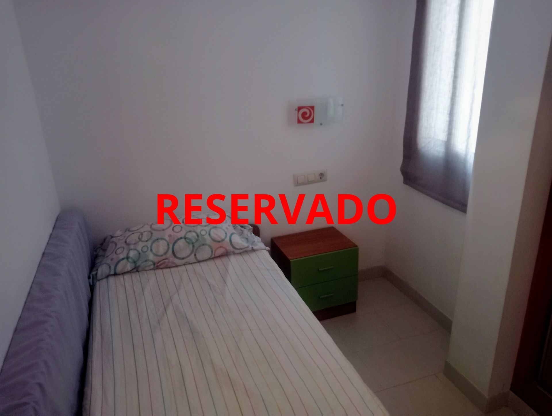 Un dormitorio con una cama individual y una mesita de noche verde.