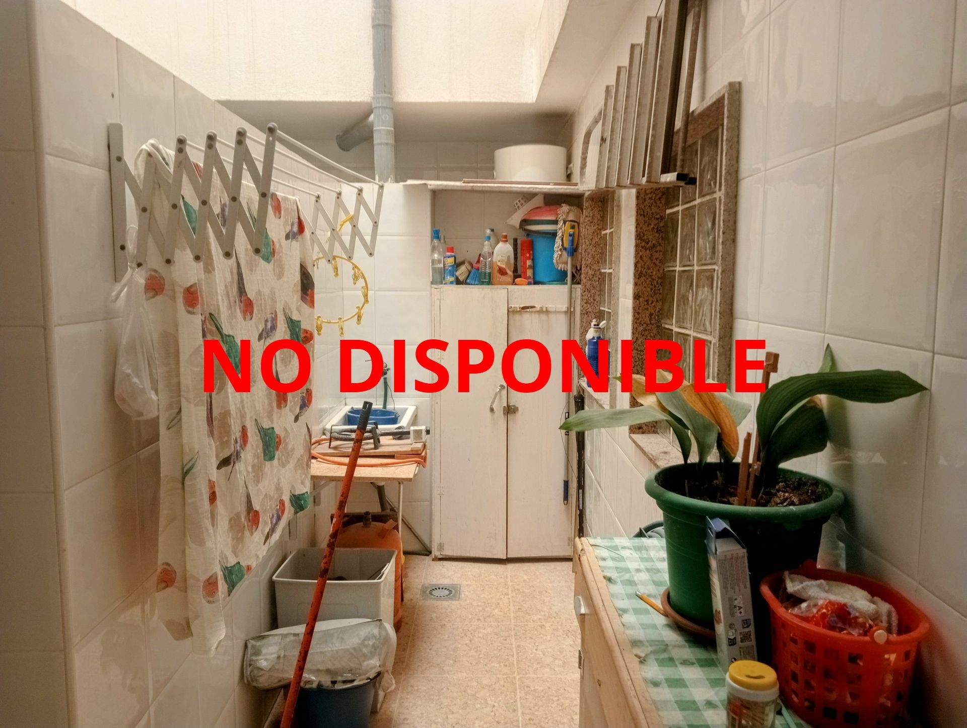 Un lavadero con un trapeador colgado en la pared y un fregadero.