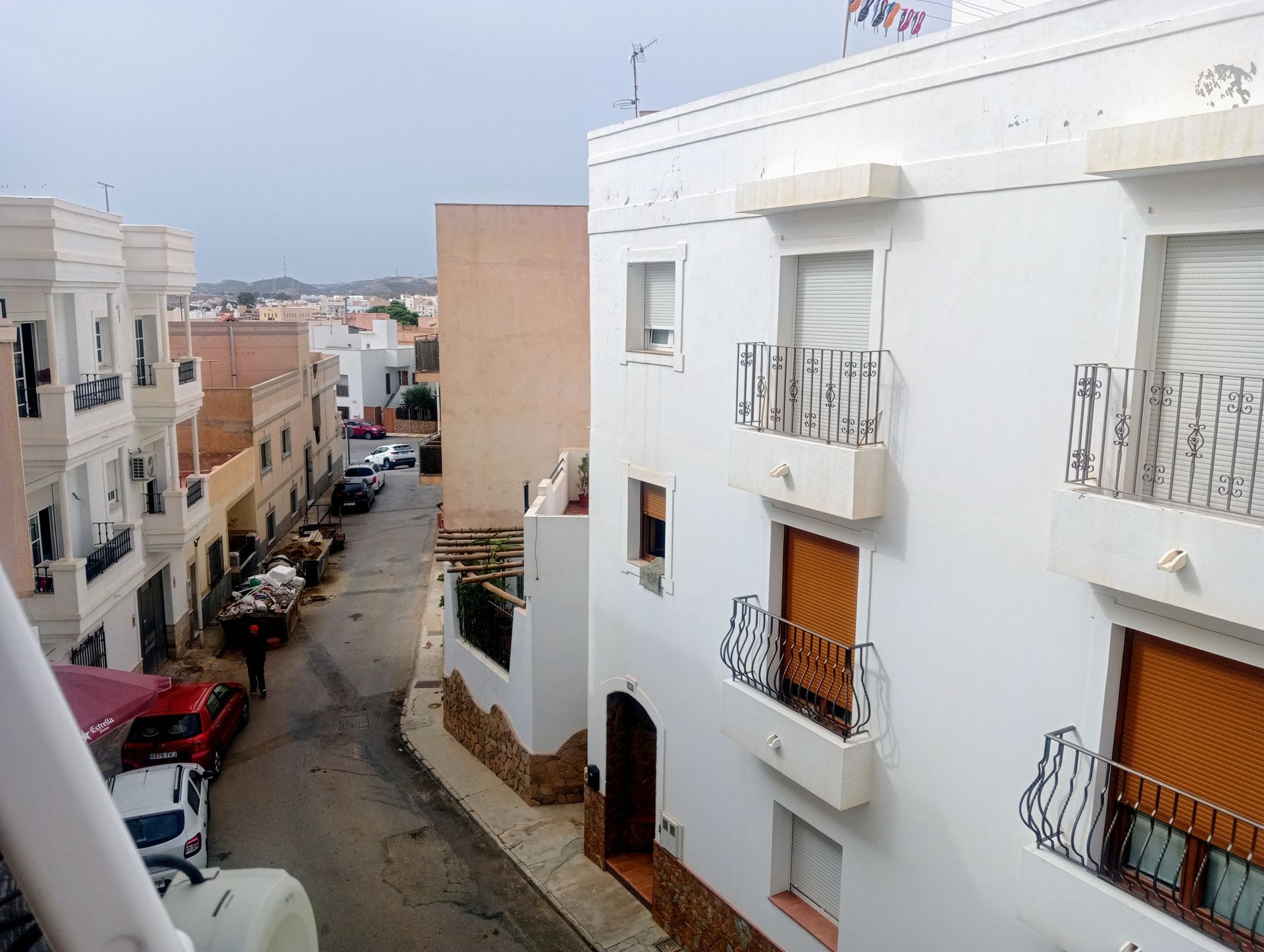 Una vista de una calle estrecha con un edificio blanco en primer plano.