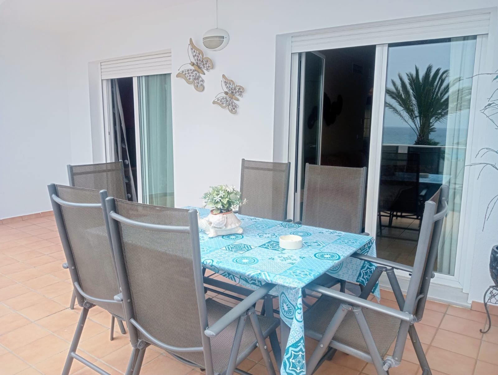 Una mesa y sillas en un balcón con un mantel azul.