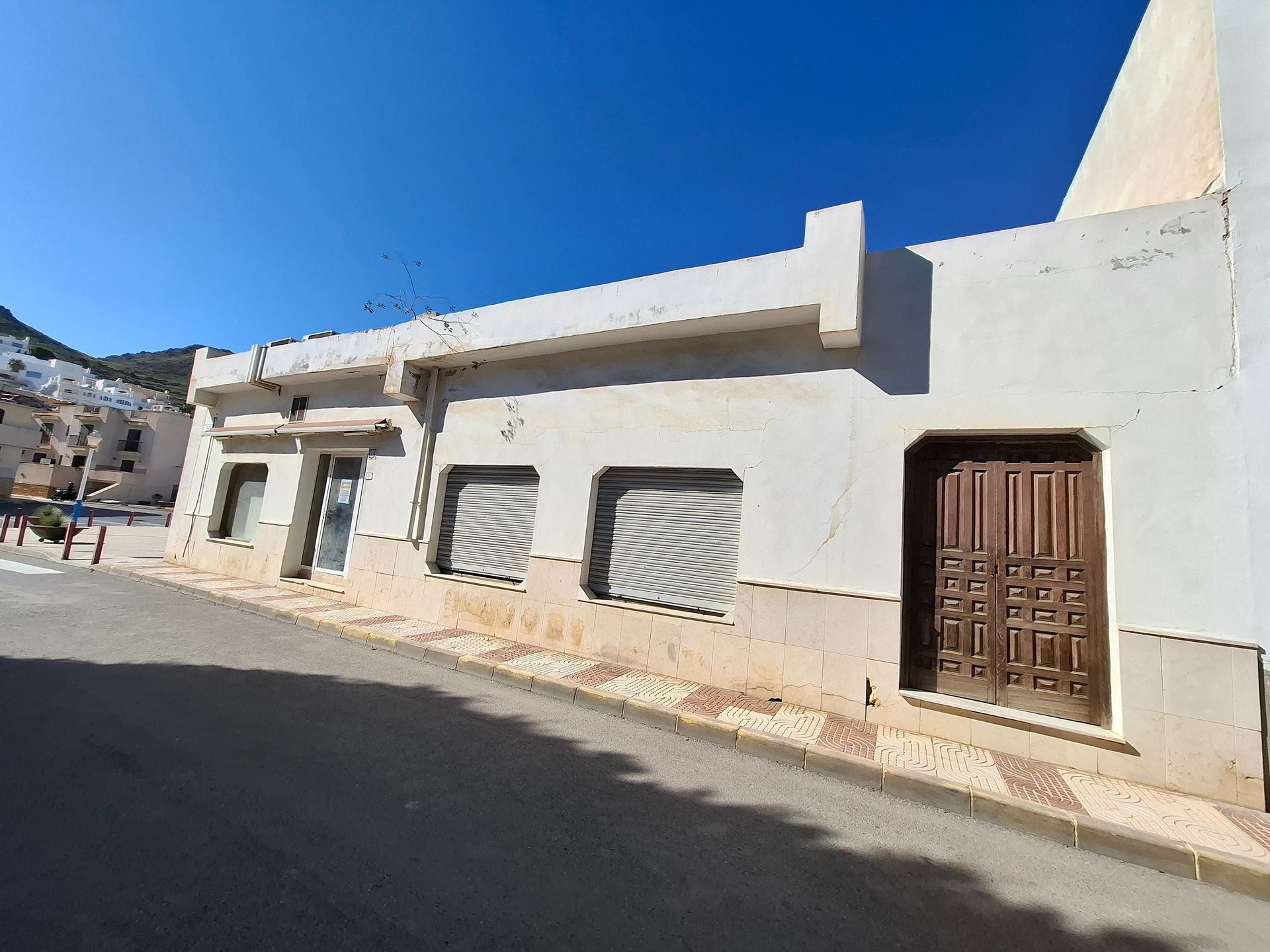 Un edificio blanco con una puerta marrón está al costado de una carretera.