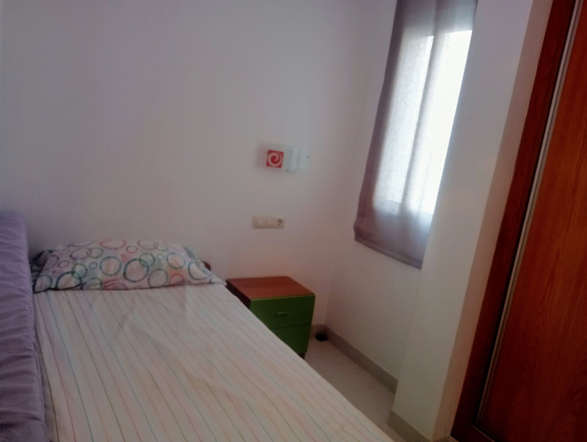 Un dormitorio con una cama individual y una mesita de noche verde.