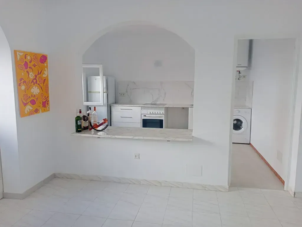 Una cocina con estufa, lavavajillas, microondas y un cuadro en la pared.