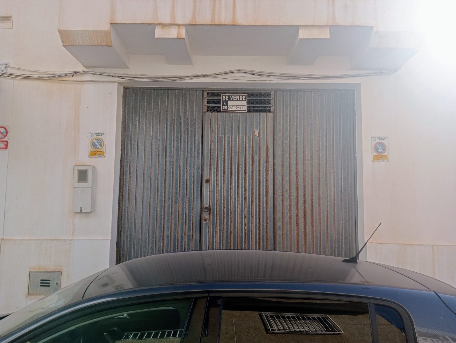Un coche está aparcado delante de una puerta de garaje.