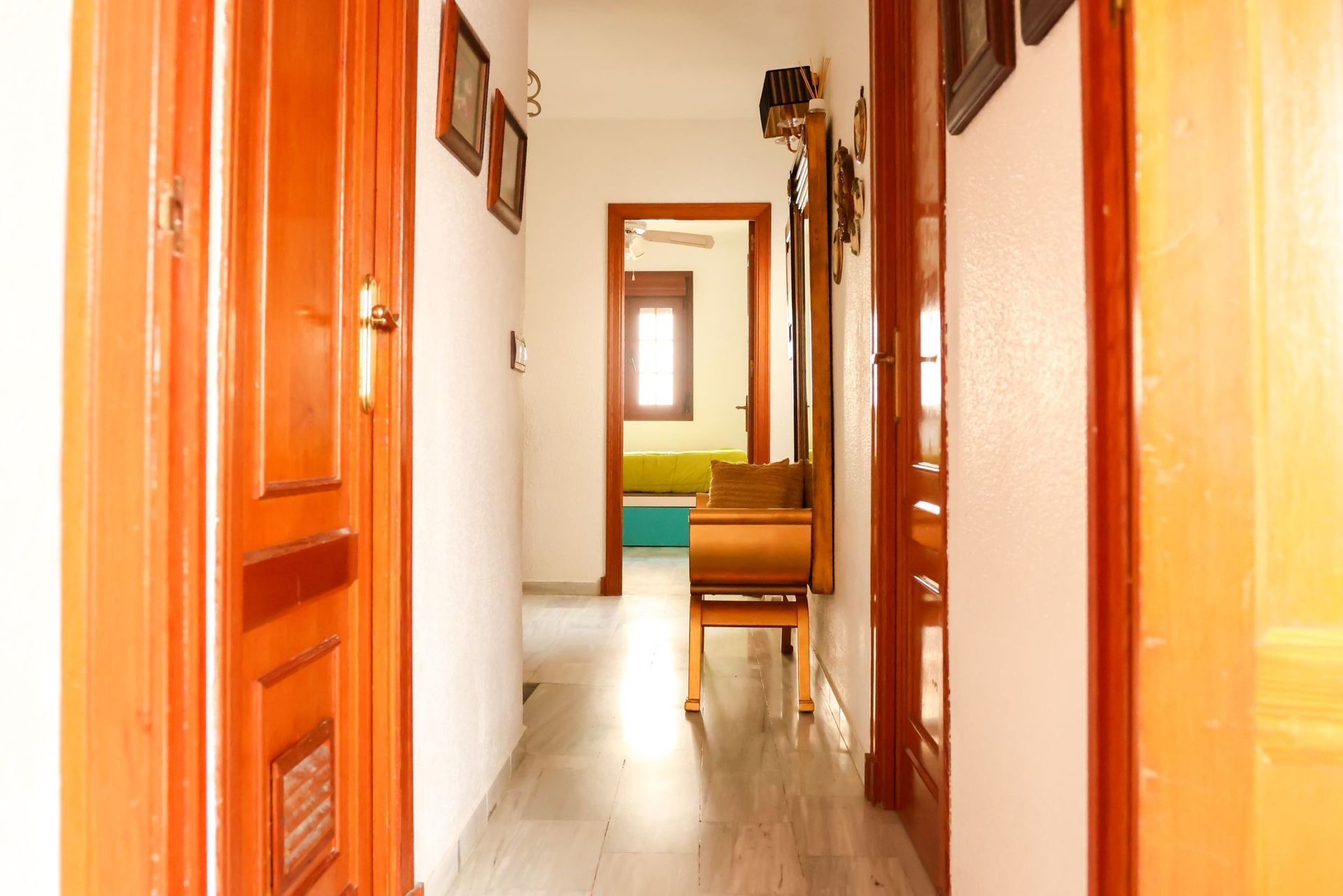 Un largo pasillo con puertas de madera que conducen a diferentes habitaciones de una casa.