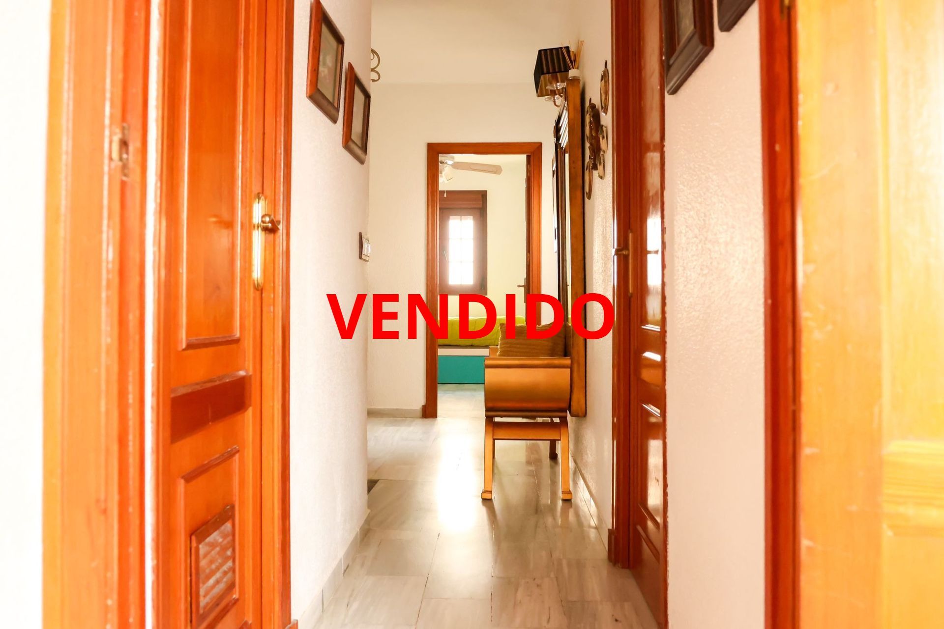 Un largo pasillo con puertas de madera que conducen a diferentes habitaciones de una casa.