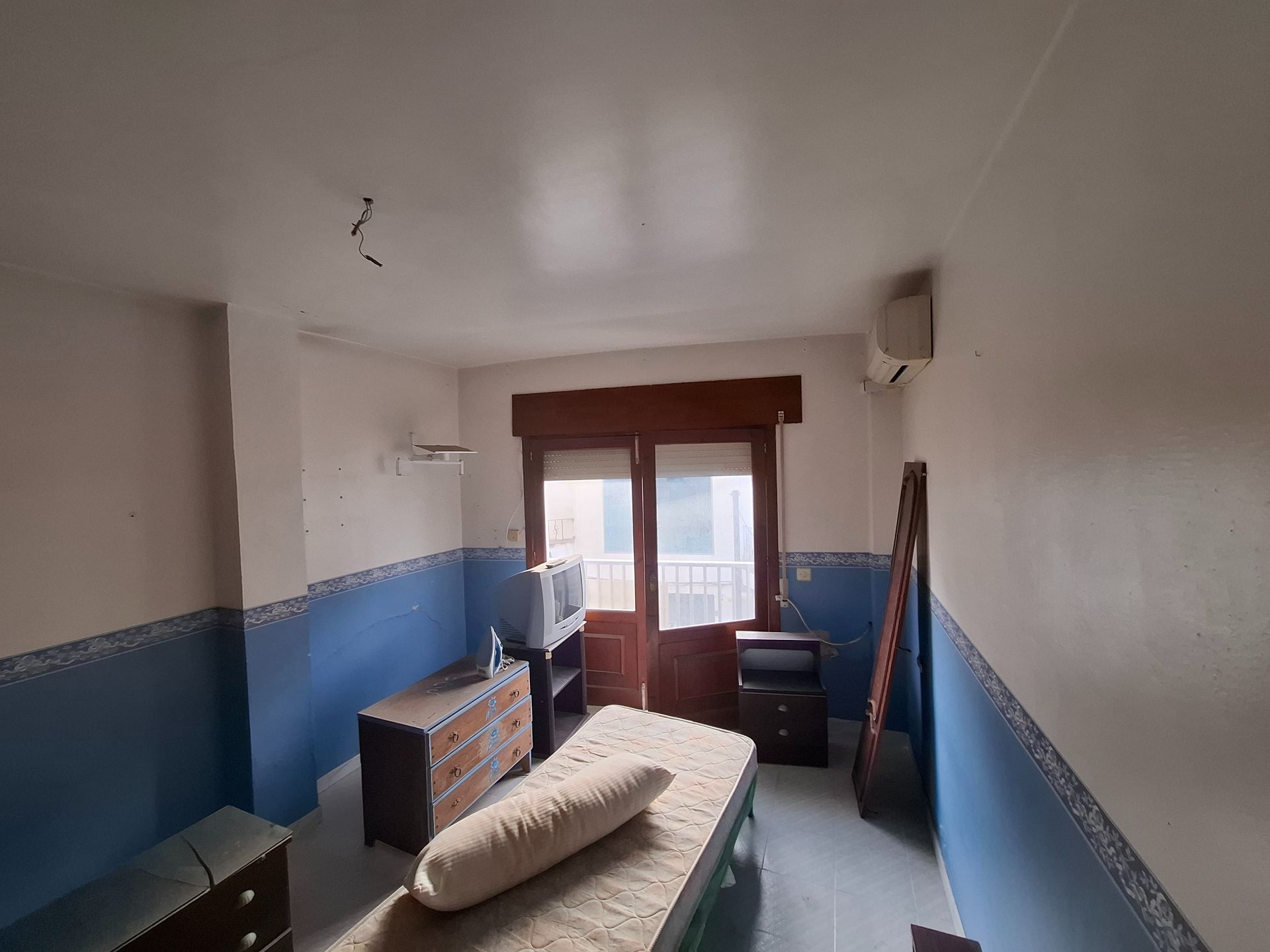 Un edificio blanco con un balcón y un cartel que dice 'alquiler'.