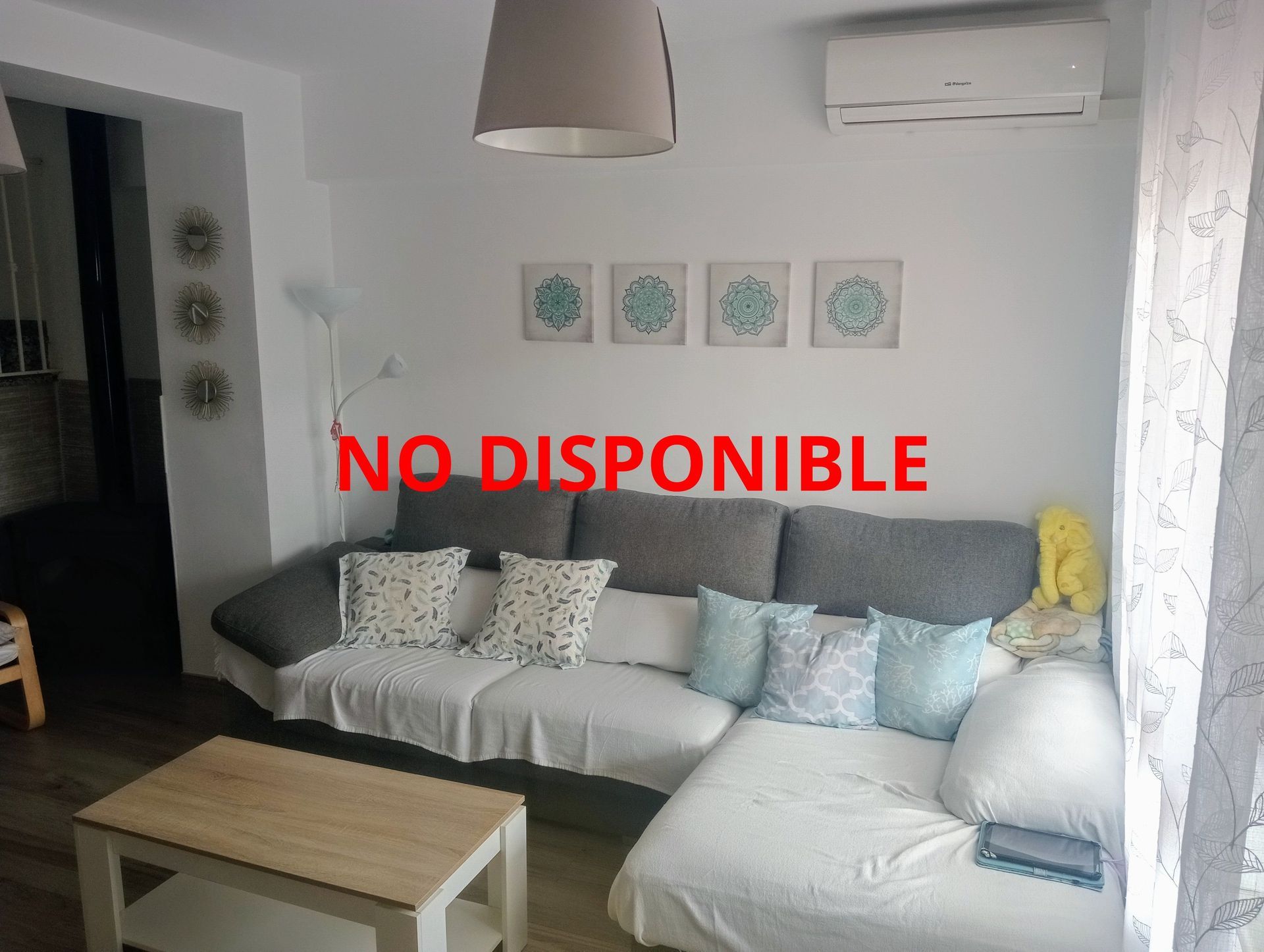 Una sala de estar con un sofá y una mesa de café y un cartel que dice no disponible.