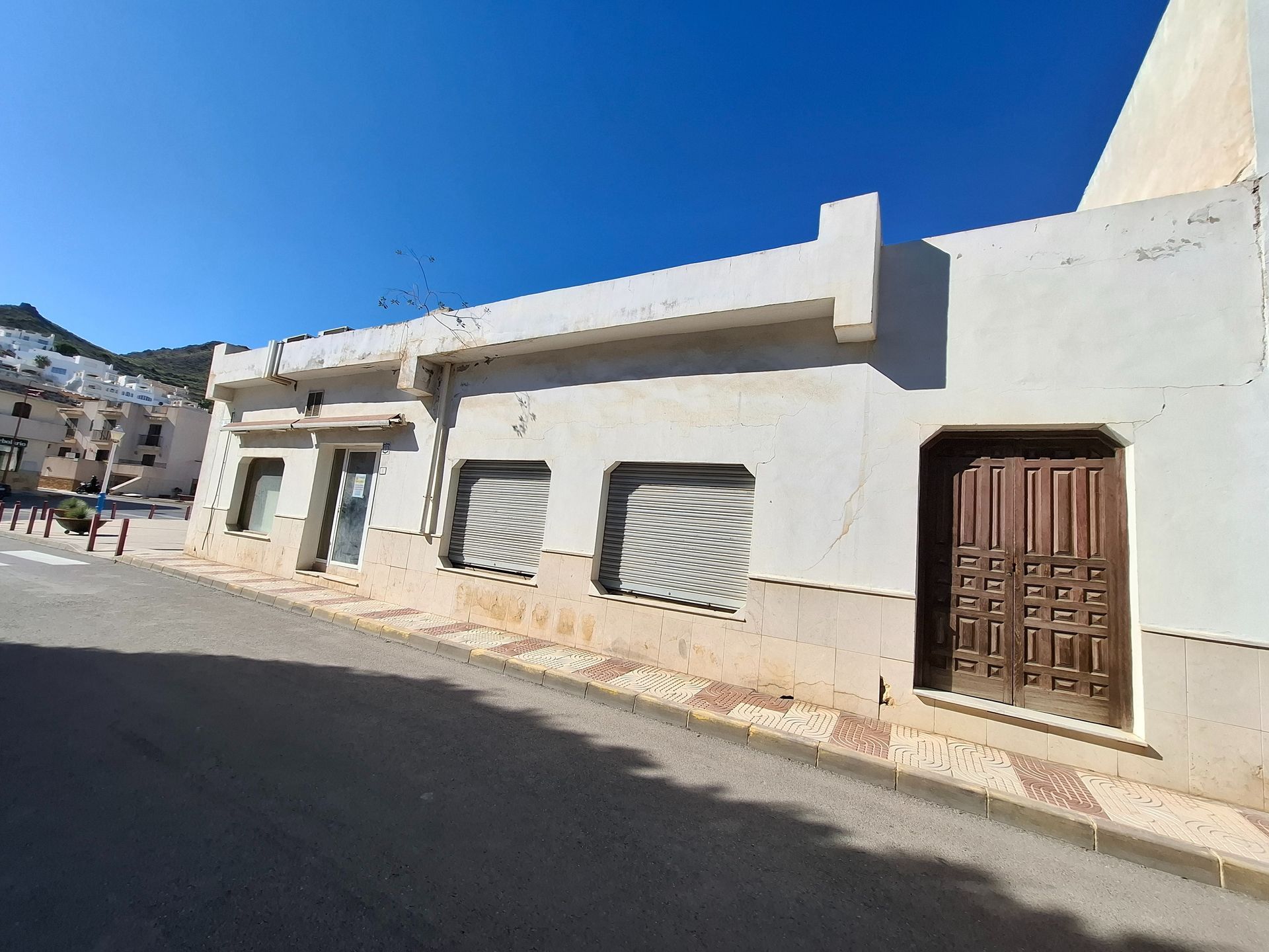 Un edificio blanco con una puerta marrón está al costado de una carretera.
