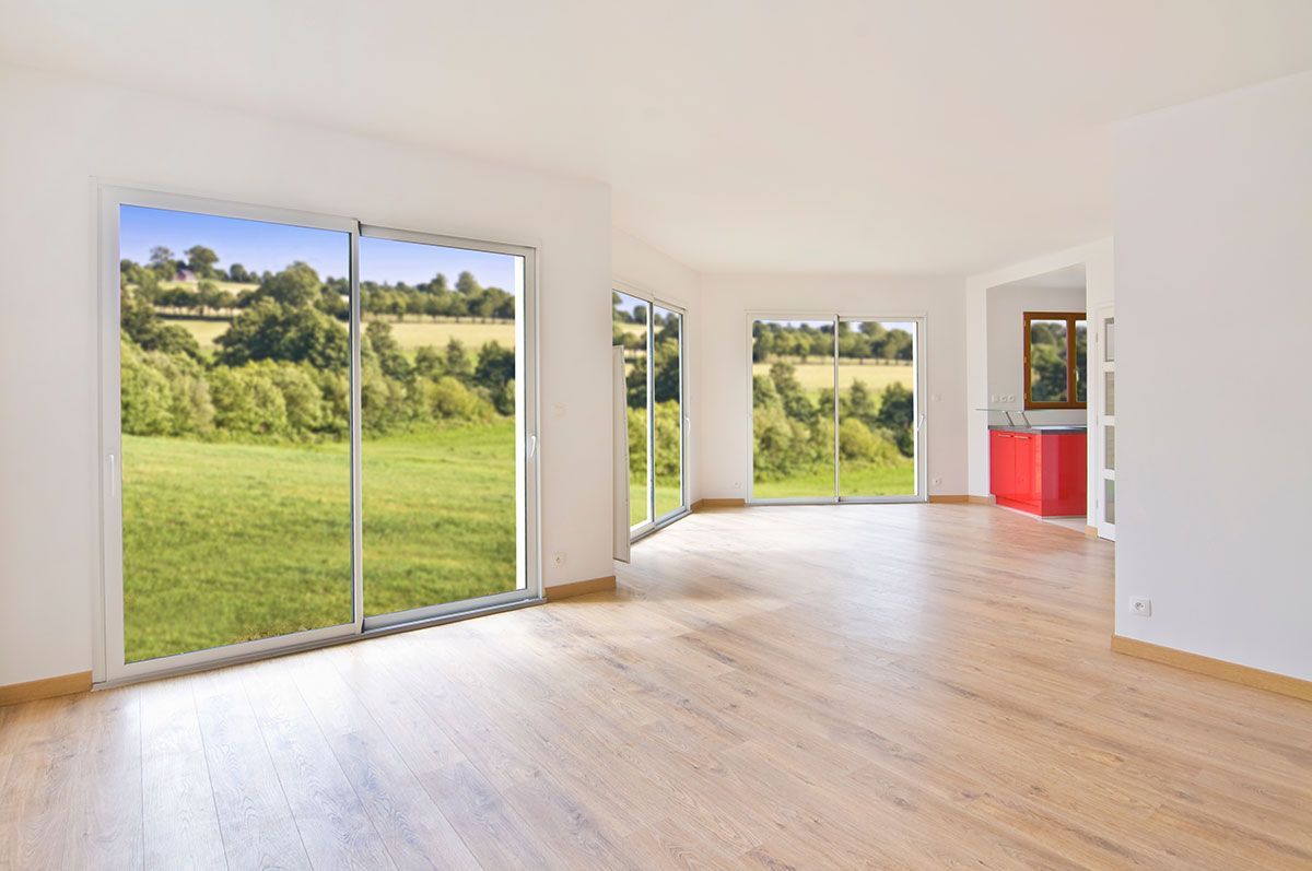 Baie vitrée dans une maison neuve avec vue sur un terrain
