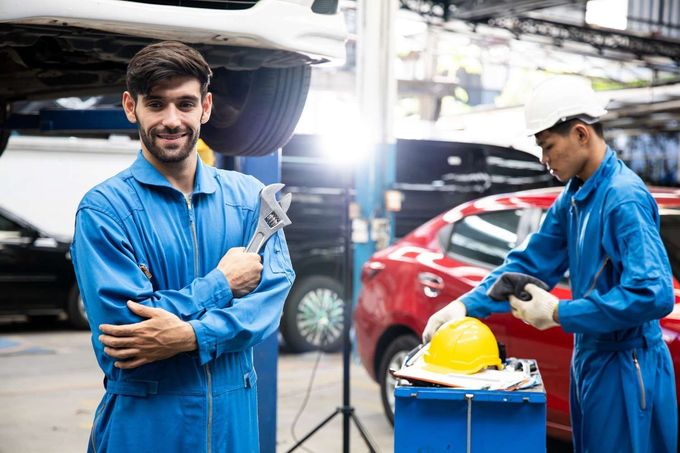 Un mecánico sonriente, con una llave inglesa en la mano
