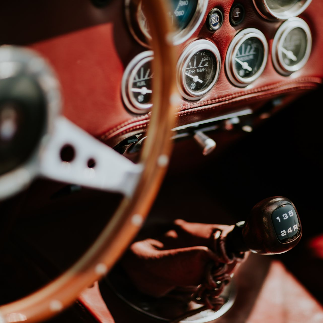 Intérieur d'une voiture avec volant en bois, tableau de bord rouge et levier de vitesses.