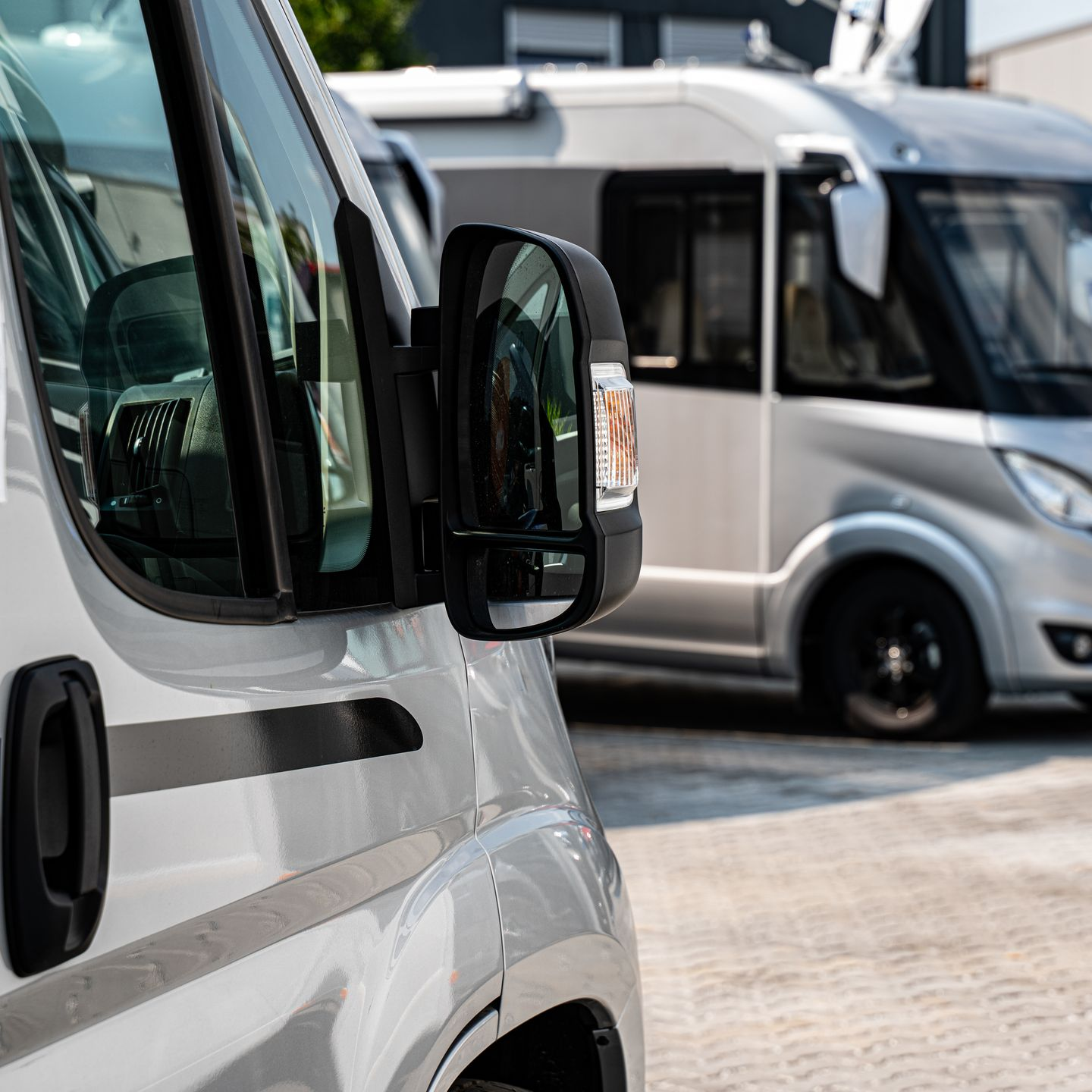 Camping-cars garés dans un stationnement avec un gros plan sur un rétroviseur.