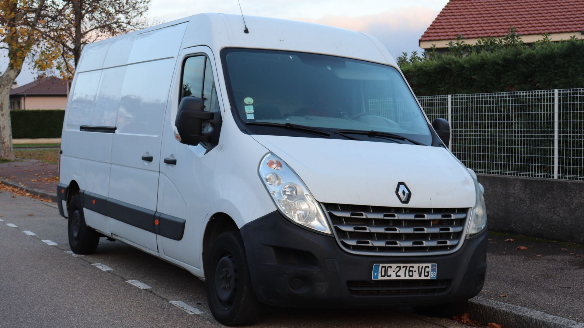 Véhicule utilitaire blanc garé le long d’un trottoir.