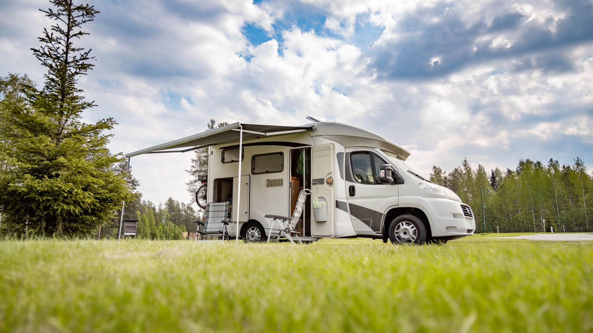 Camping-car arrêté sur une pelouse avec auvent déployé.