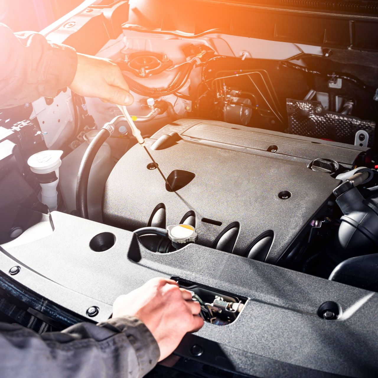 Mains vérifiant une jauge d’huile dans le compartiment moteur.