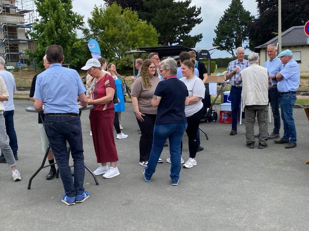Gruppe von Menschen, die sich im Freien unterhalten, grauer Asphalt, bewölkter Tag.