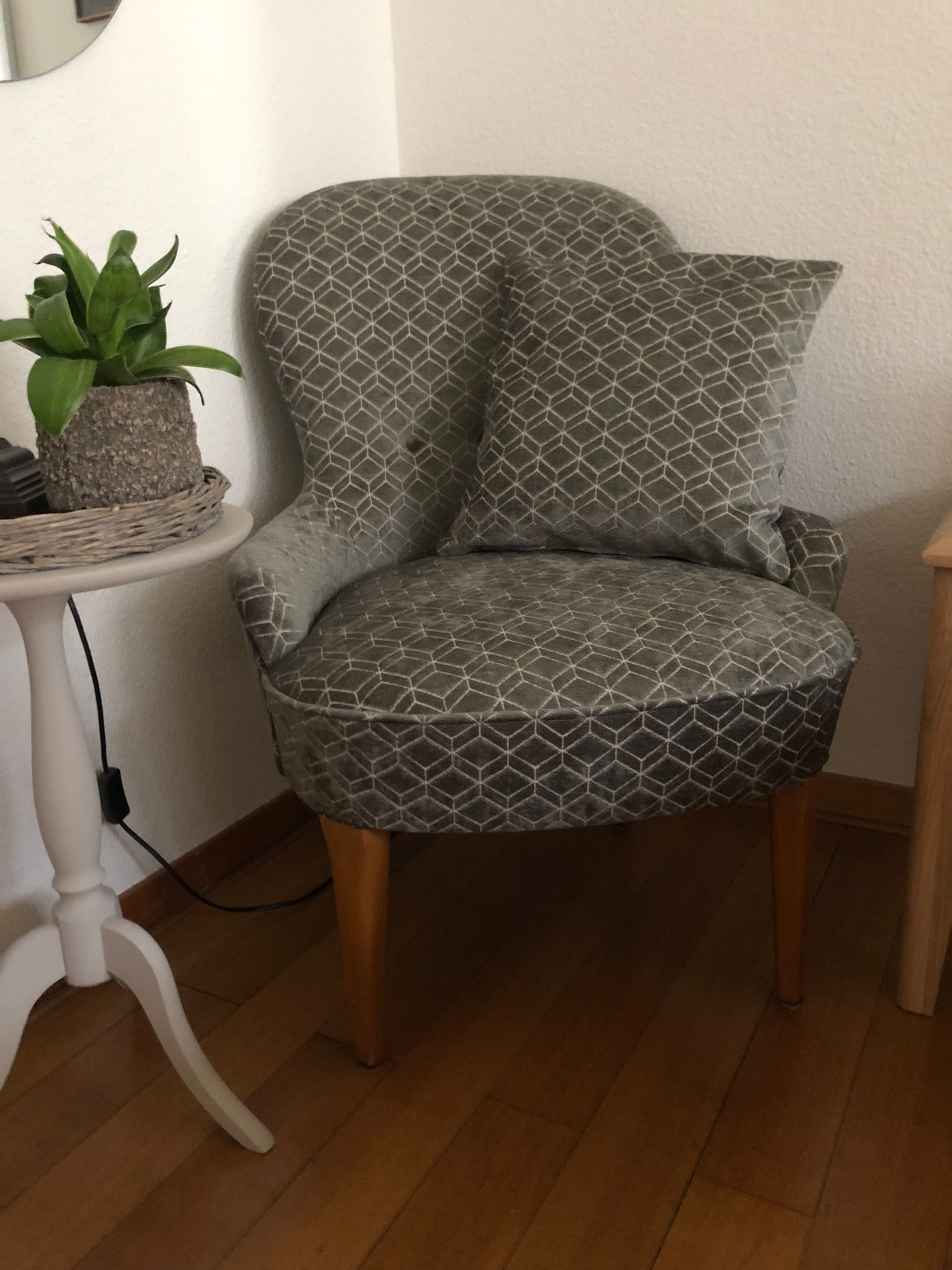 Neben einem Tisch steht ein Stuhl mit einem Kissen darauf.