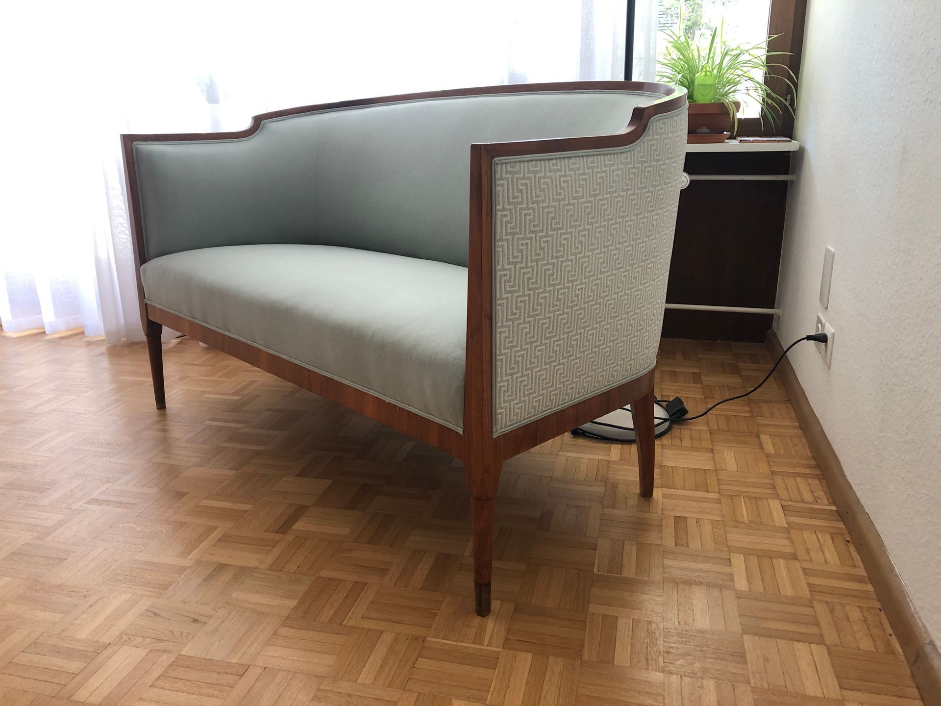 In einem Zimmer steht eine Couch auf einem Holzboden.