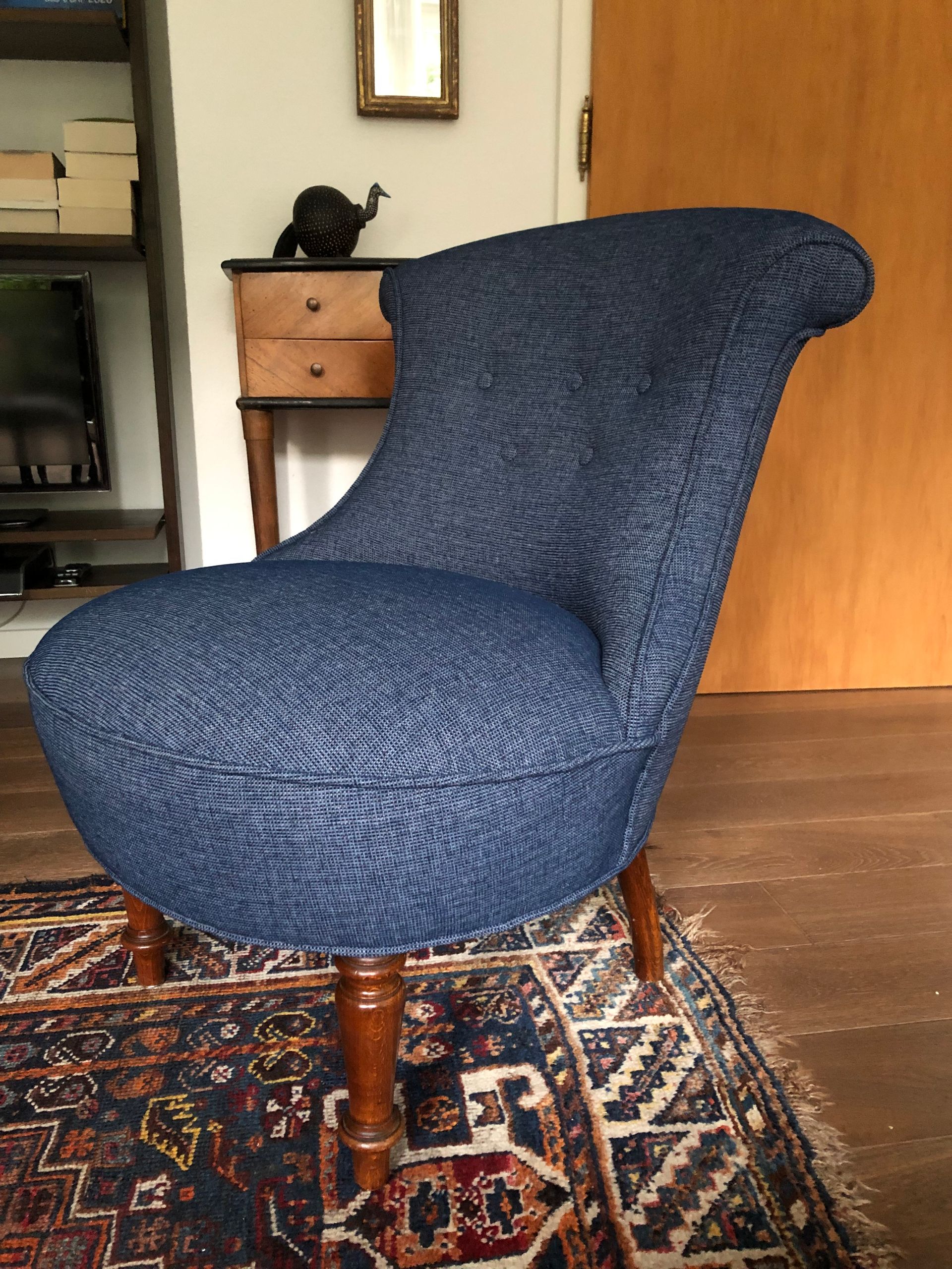 Ein blauer Stuhl steht auf einem Teppich in einem Wohnzimmer.