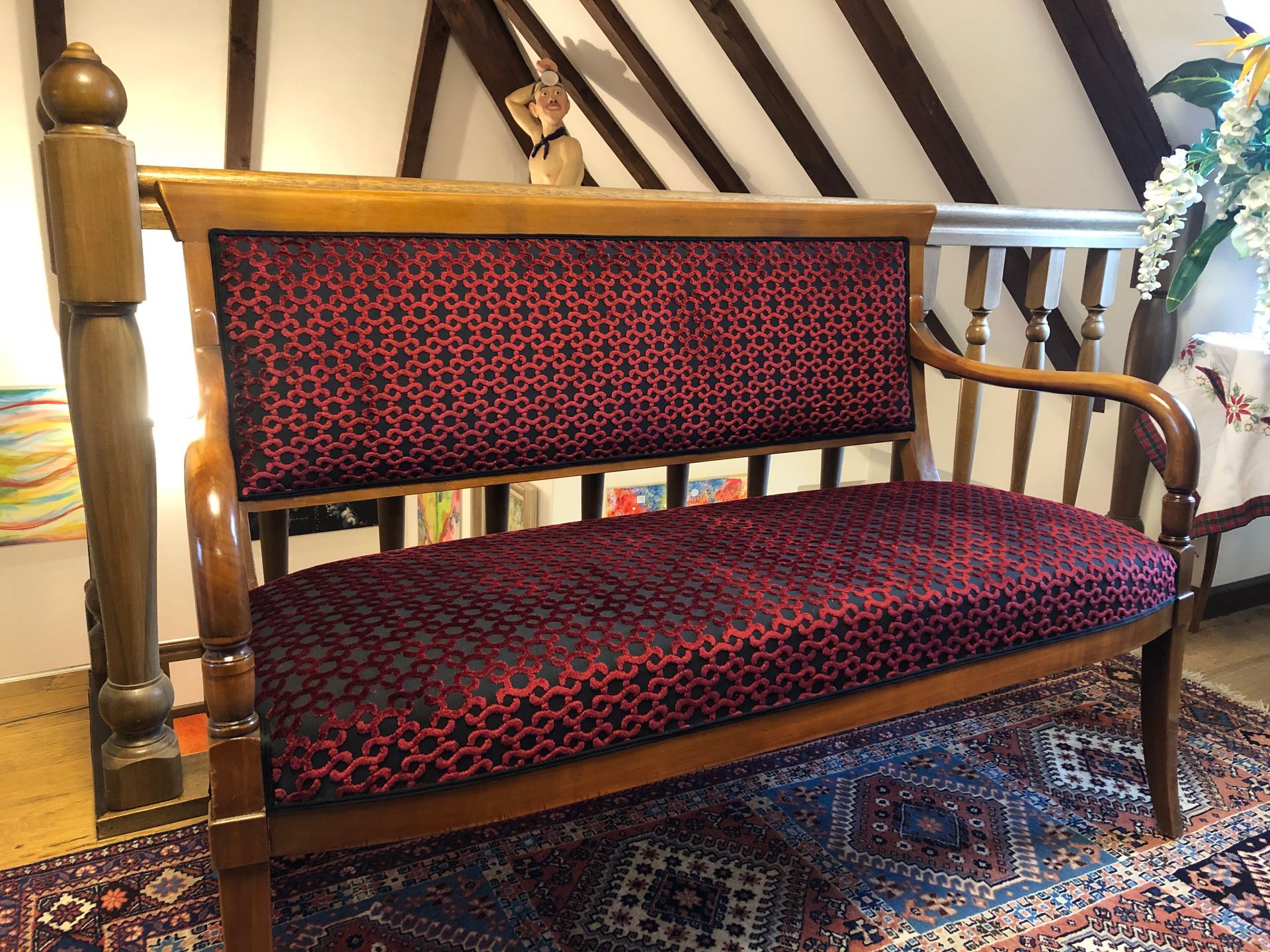 In einem Raum neben einer Treppe steht ein rotes Sofa auf einem Teppich.