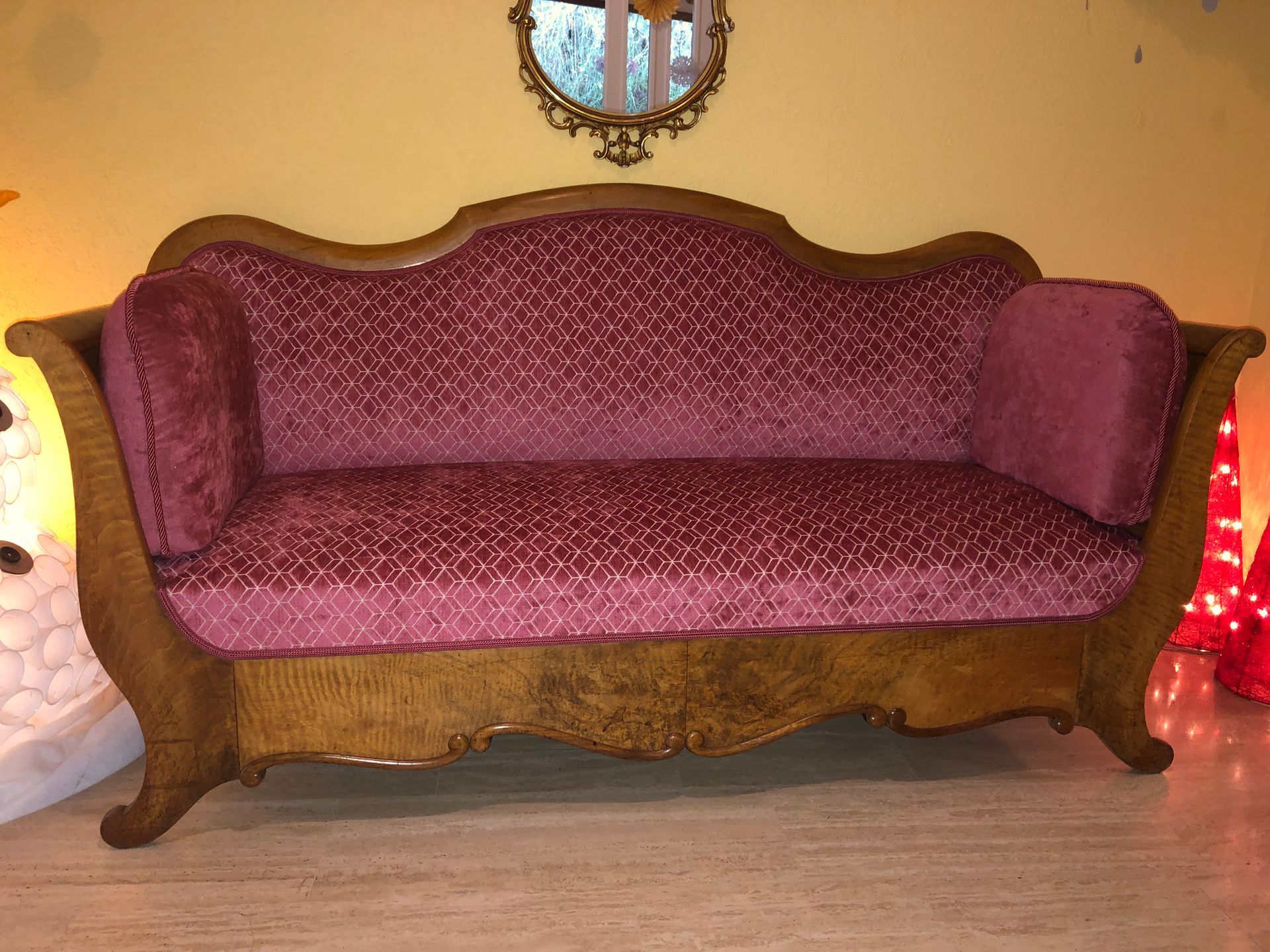 In einem Wohnzimmer steht ein lila Sofa neben einem Spiegel.