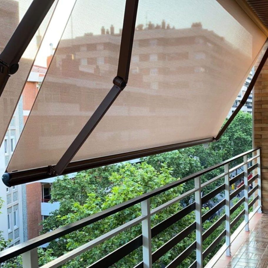 Un balcón con un toldo marrón encima.