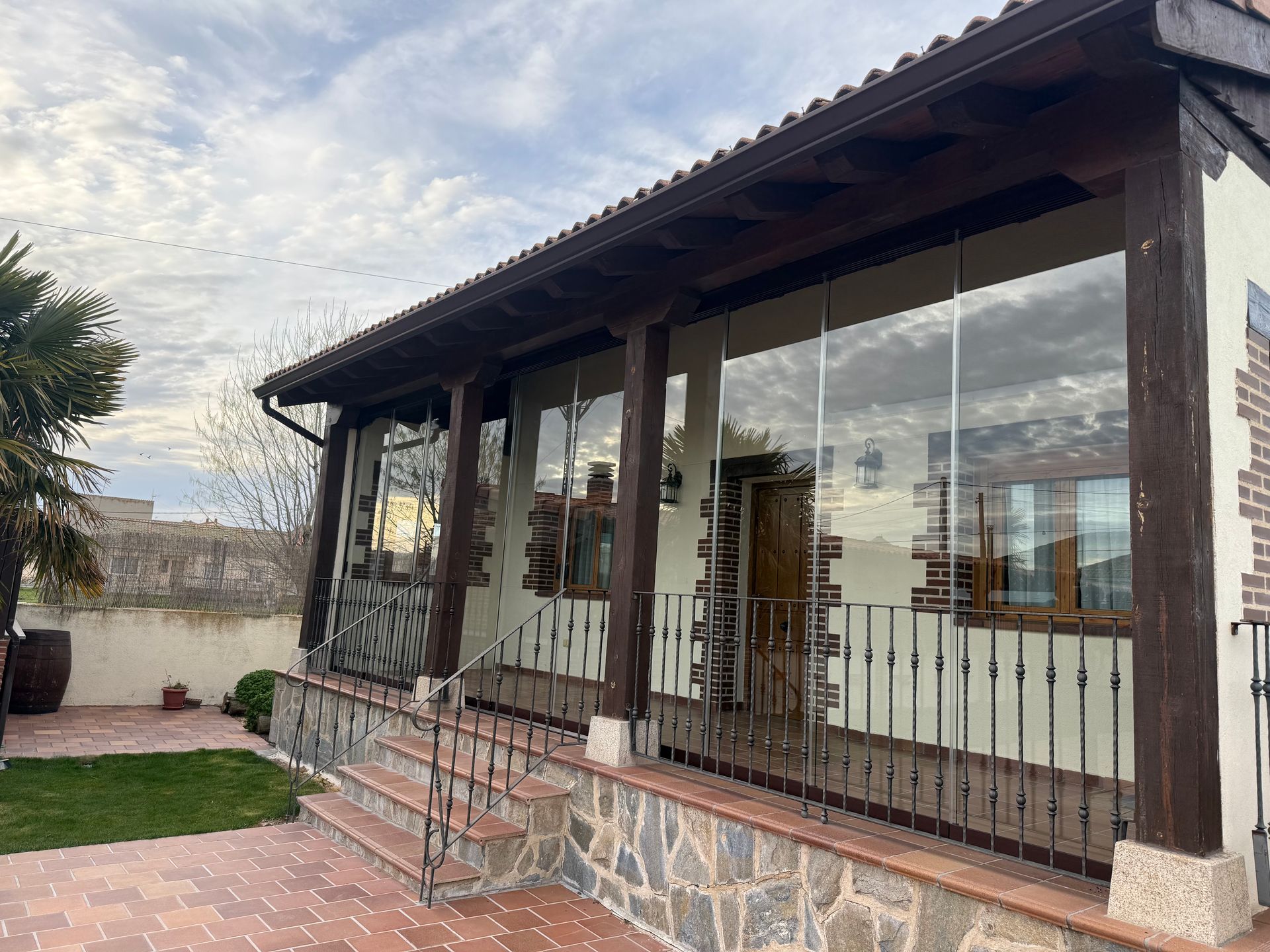Vista exterior de una casa con porche de madera acristalado con cerramieinto corredero