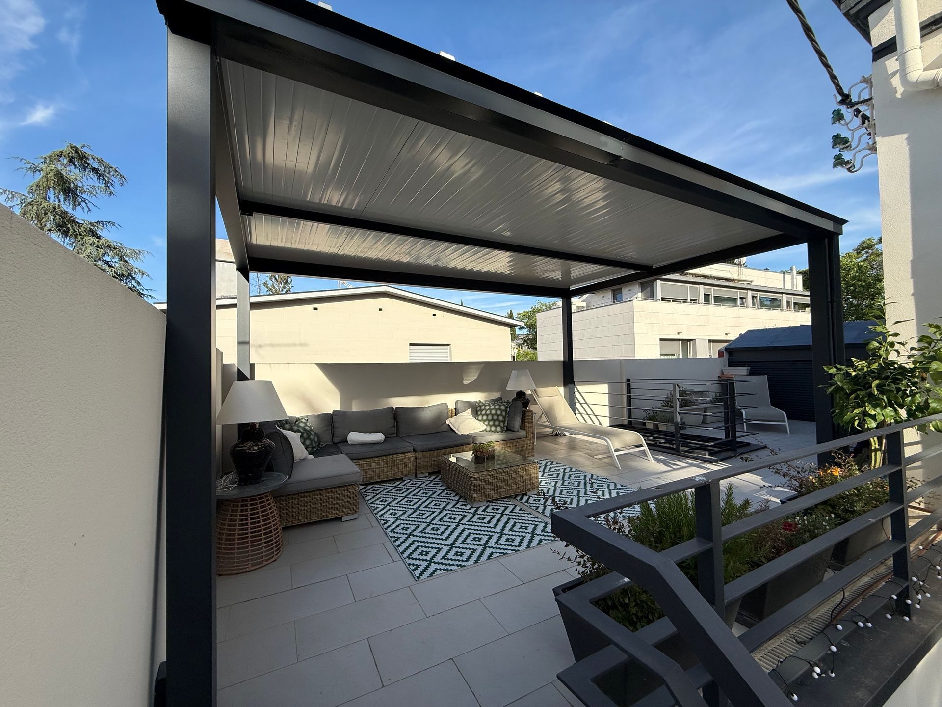 Moderna terraza acristalada con paredes de cristal, zona de comedor y zona de estar, situada sobre una terraza de madera