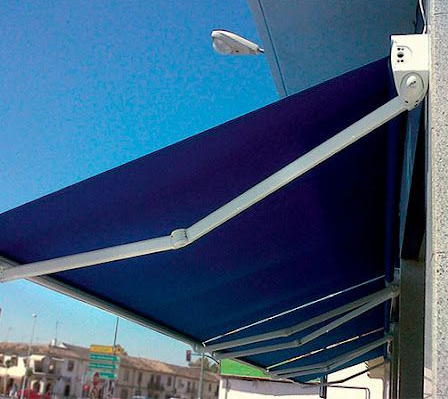 Patio en la azotea con muebles grises, mesas de madera y pérgola negra ajustable