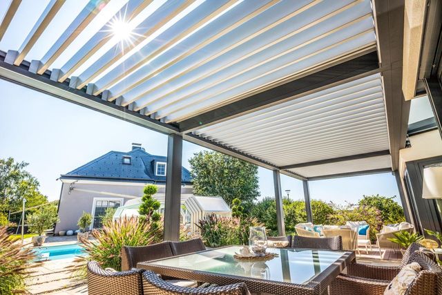 Un patio con una mesa y sillas bajo una pérgola.