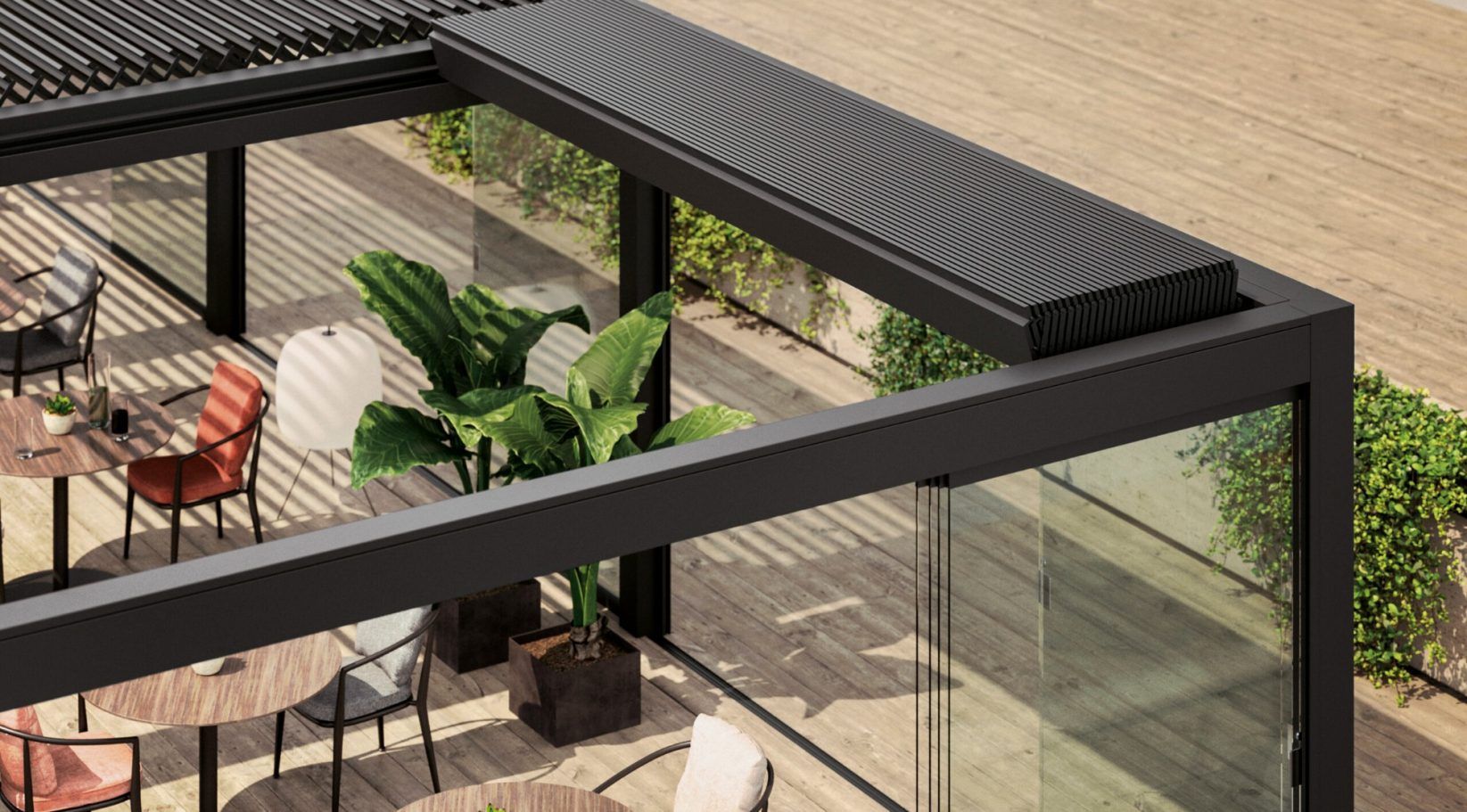 Moderno patio exterior con pérgola negra, paredes de vidrio, mesas, sillas y plantas.