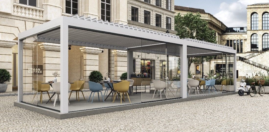 Cafetería al aire libre con cortina de cristal, mesas y sillas, bajo una pérgola bioclimática blanca