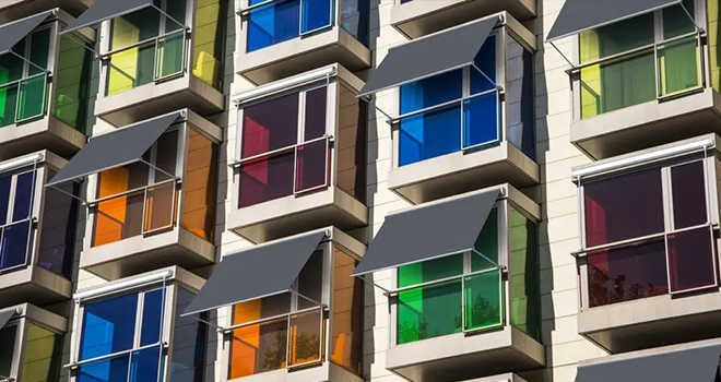 Patio al aire libre con techo retráctil, pared de ladrillo, puertas de vidrio y mesa y sillas turquesas.