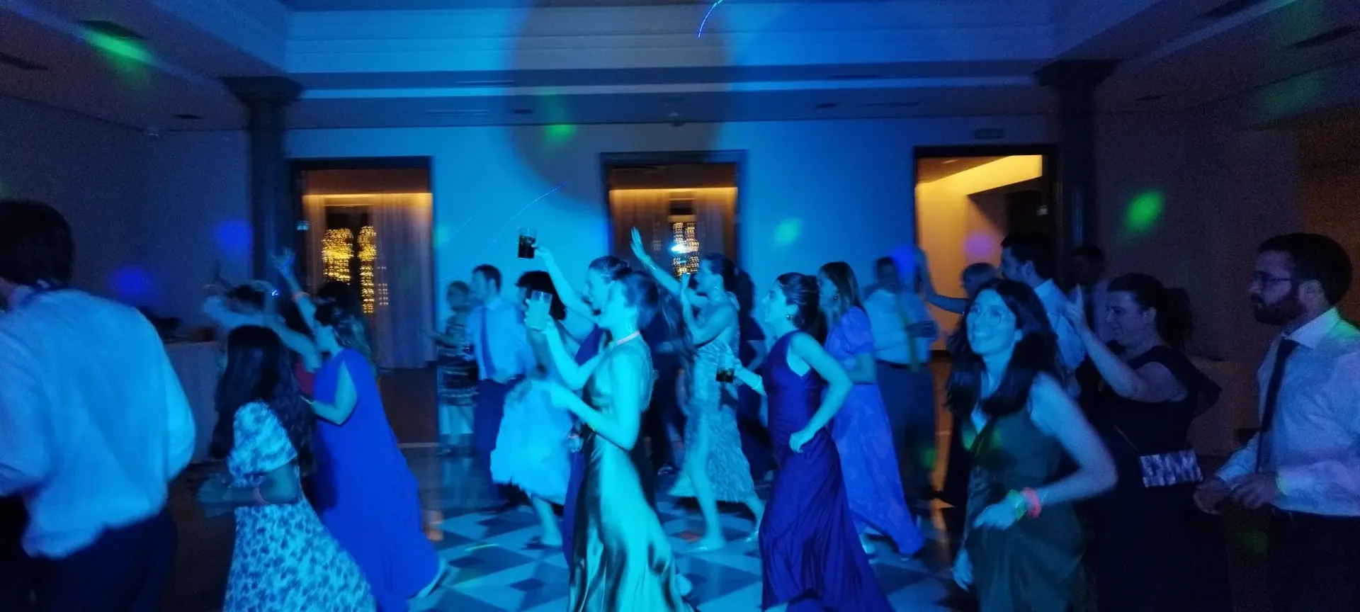 Un grupo de personas está bailando en una habitación con luces azules.