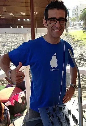 Un hombre que lleva auriculares y una camisa azul con una manzana encima está haciendo un gesto de aprobación con el pulgar hacia arriba.