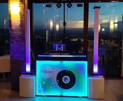 Una cabina de DJ con un disco encendido está iluminada por la noche.
