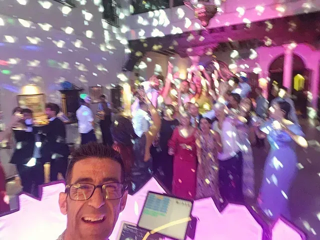 Un hombre se toma una selfie frente a una multitud de personas en una fiesta.