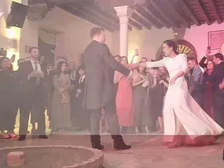 Una novia y un novio están bailando frente a una multitud en una recepción de boda.