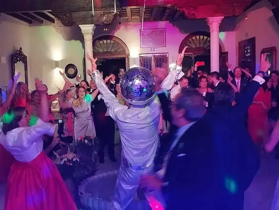 Un grupo de personas está bailando en una habitación con una bola de discoteca en el medio.