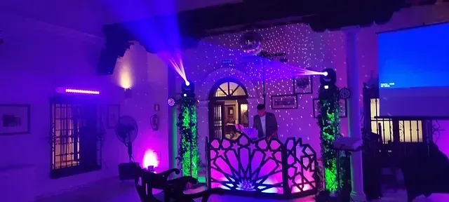 Un hombre está de pie en un escenario en una habitación con luces moradas y verdes.