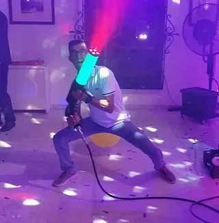 Un hombre está arrodillado en una habitación con luces violetas detrás de él.