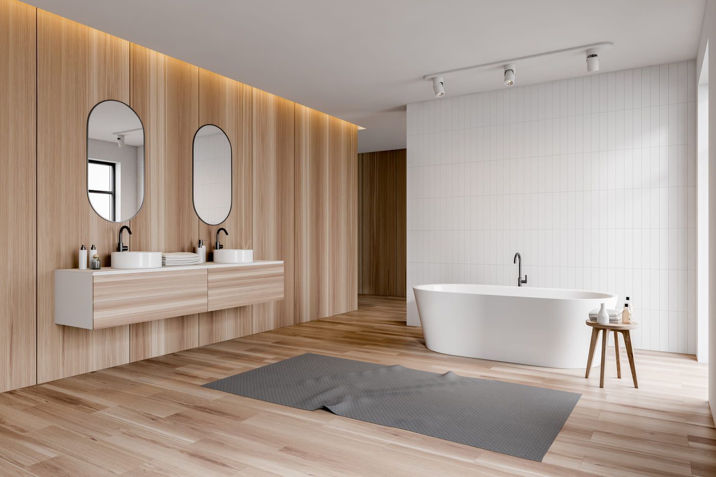 Baño moderno con paneles de madera, tocador flotante y bañera exenta. La habitación cuenta con luz natural y una alfombra gris cubre el suelo de madera.