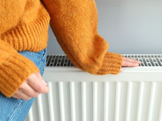 Electricista con ropa de trabajo verde que usa un destornillador para trabajar en un panel eléctrico con cables e interruptores.