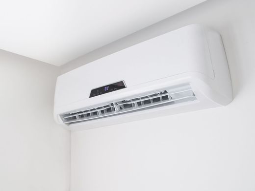 Electricista con ropa de trabajo verde que usa un destornillador para trabajar en un panel eléctrico con cables e interruptores.