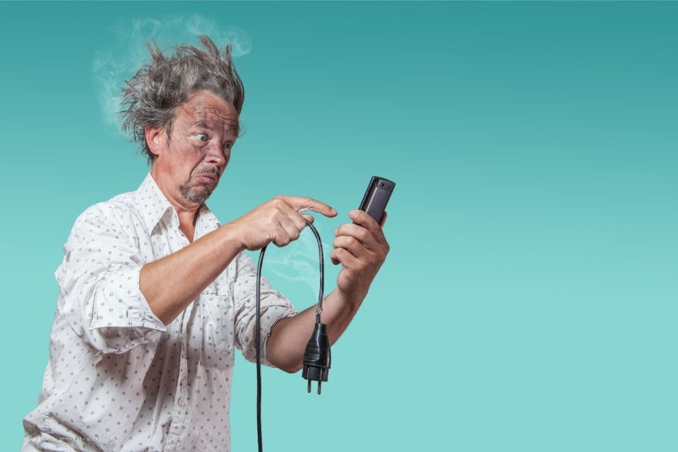 Mensch mit strubbeligen Haaren, vermeintlich nach Stromkontakt, ruft Elektriker an
