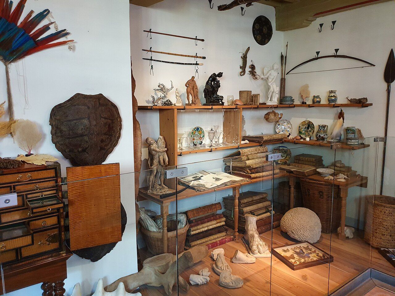 Museum display of handcrafted artifacts on shelves and tables in a small exhibit room